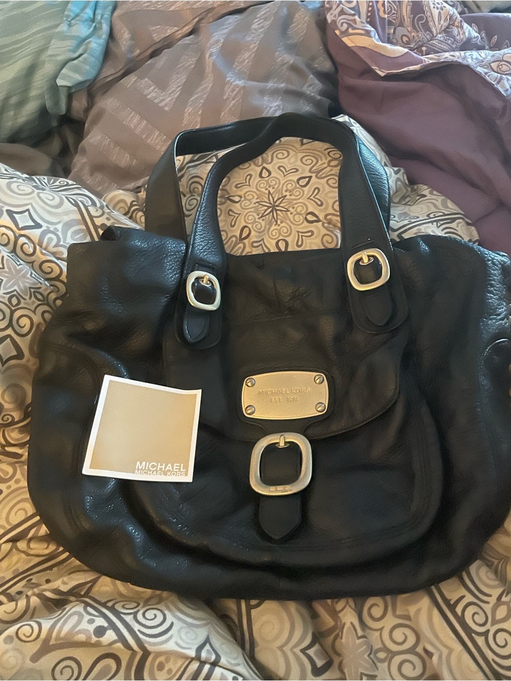 Michael Kors Hudson Black Pebbled Leather bag with gold hardware and buckles.